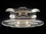 un service en argent ancien composé d'un bol et d'une soucoupe, sur fond noir