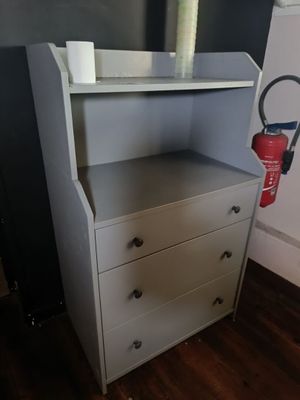 une commode blanche sur laquelle est posé un extincteur