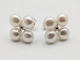une paire de boucles d'oreilles en perles blanches et argent posées sur un fond blanc