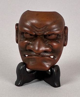 an image of a wooden sculpture of a man ' s face on a stand