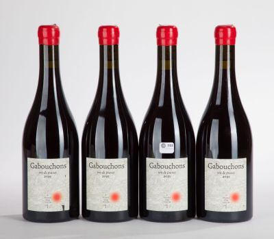 trois bouteilles de vin rouge sont alignées sur une surface blanche