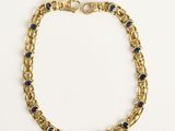 Gros plan sur un bracelet en or orné de pierres bleues