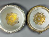 two white and gold plates with gold designs on them on a table