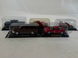 four toy cars in a display case on a white surface
