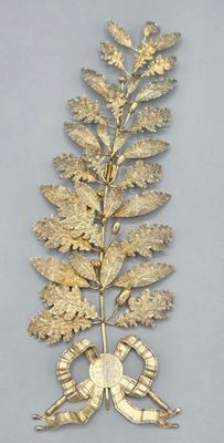 broche en forme de feuille plaquée or, ornée d'un nœud et d'un ruban