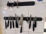 a bunch of knives hanging on the wall in the kitchen