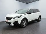 Une voiture blanche est garée dans une pièce blanche au sol noir.
