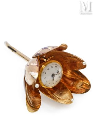 une petite fleur en or sur laquelle est représentée une horloge