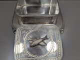 a silver plate with a bird on it and a silver plate with a bird on it