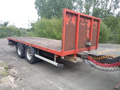 un camion à plateau rouge garé sur un parking