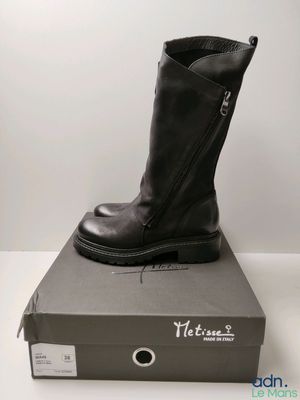 les bottes noires sont posées sur la boîte, sur la table