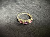 a close up of a gold ring with pink stones