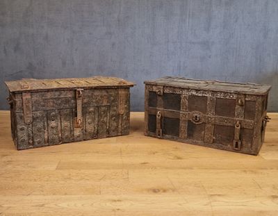 paire de malles anciennes en bois avec des poignées métalliques, posées sur le sol en bois