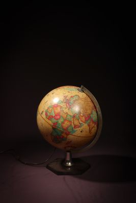 an old globe on a stand in the dark with a light shining on it