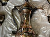 une théière en argent et en or posée sur une nappe blanche
