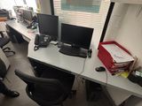 a man sitting at a desk with two computers on it