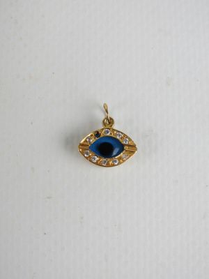 un pendentif « œil maléfique » doré et bleu sur un fond blanc