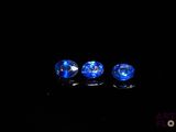 three blue glass beads sitting on top of a black surface