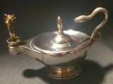 a silver teapot with a snake handle on a table