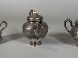 trois théières en argent et un sucrier posés sur une table