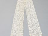 un pantalon en dentelle blanche posé sur une surface grise