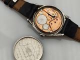 a watch sitting next to a coin on a table