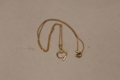 a close up of a gold necklace with a heart on it