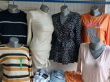 Plusieurs mannequins sont alignés sur une table, à côté de cartons de vêtements