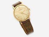 gros plan d'une montre sur une surface blanche avec un bracelet marron