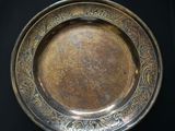 a silver plate on a stand on a black surface