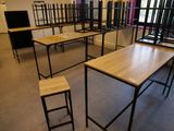 Des tables et des tabourets sont disposés dans une pièce avec une fenêtre à l'arrière-plan.