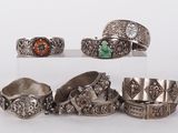 several different types of silver rings and bracelets on a white surface