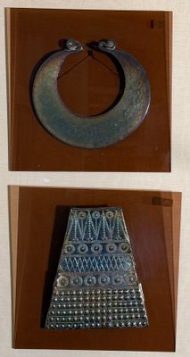 two pictures of a metal object on display in a glass case