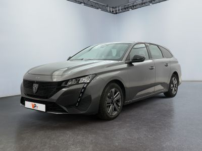 Une voiture grise est garée dans une pièce blanche au sol noir.