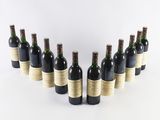 six bottles of wine lined up in a row on a white surface
