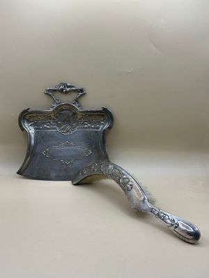 un plat ancien en argent, muni d'une poignée, posé sur une table