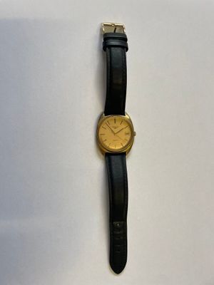 une montre en or posée sur un bracelet en cuir noir