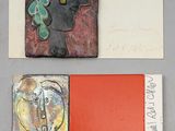 Plusieurs œuvres d'art sont exposées sur une table où se trouve un livre rouge