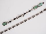 two pieces of silver and green glass bracelets on a white surface