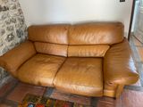 a brown leather couch sitting in front of a stone wall
