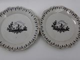two plates with black and white designs on them sitting on a table