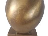a gold sculpture of a ball on a wooden base