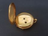 a gold pocket watch that is on a black surface