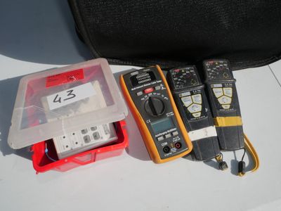 three multimeters sitting on a table next to a case