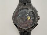 La montre est noire et est munie d'un bracelet noir qui entoure le poignet.