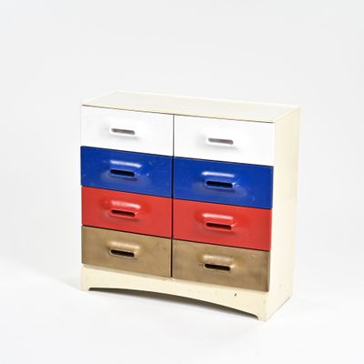 une petite commode en bois dont les tiroirs sont rouges, blancs et bleus
