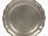 une assiette ancienne en argent aux bords festonnés sur fond blanc