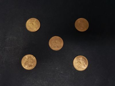 six pièces d'or sont disposées en cercle sur une surface noire