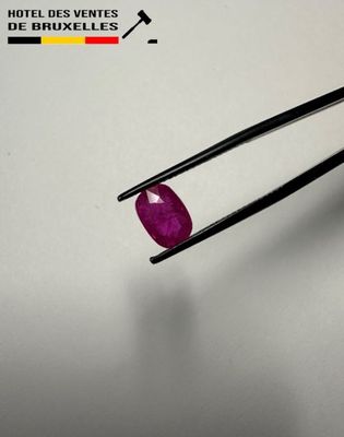 a close up of a pair of tongs holding a ruby stone