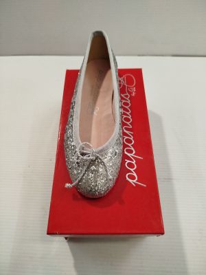 quelqu'un porte une paire de chaussures argentées posées sur une boîte rouge